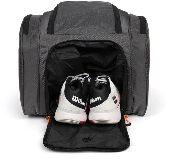 Open donkergrijze sporttas met een paar witte en zwarte sportschoenen erin.