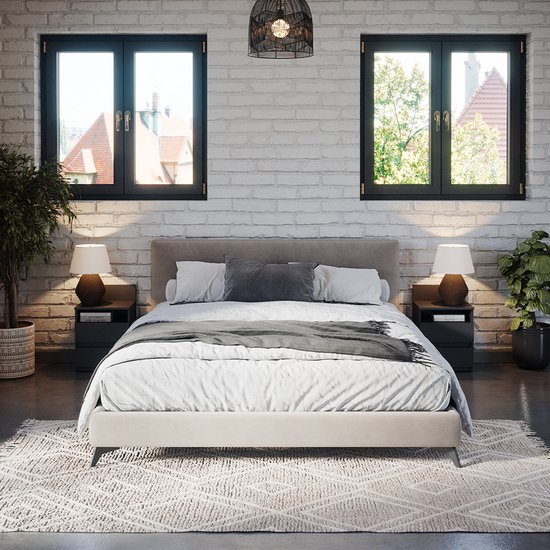 Une chambre avec un lit double, deux tables de nuit noires avec lampes, un tapis et des plantes.