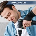 Een man met een blauwe spijkerblouse die een zwarte polsbrace draagt tijdens het boren.