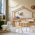Wit Alpaca hobbelpaard in een kinderkamer, naast een houten tafel en stoelen.