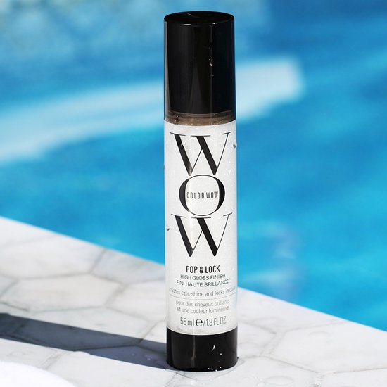 Een flesje Color Wow Pop & Lock High Gloss Finish, 55 ml, staat op een tegelrand bij een zwembad.