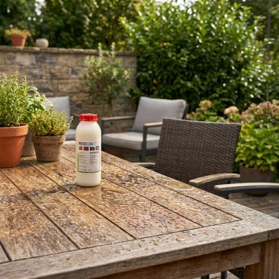 Houten tuintafel met waterdruppels. Fles WOODCON, plantenpotten en tuinmeubels op de achtergrond.