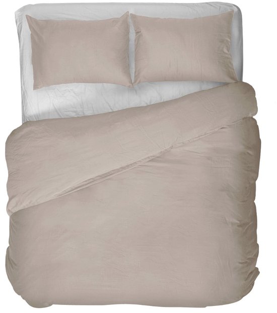 Een tweepersoonsbed met een lichtbruin dekbedovertrek en twee bijpassende kussenslopen.