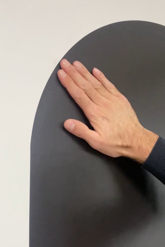 Main sur un tableau noir en forme d'arche.
