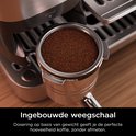 Detailopname van de zilverkleurige Ninja koffiemachine met een volle portafilter met gemalen koffie.