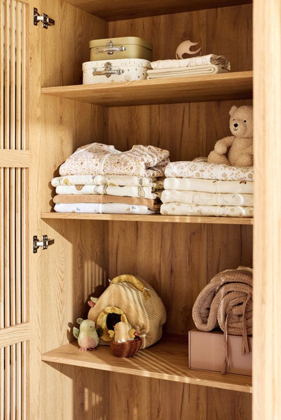 Opbergkast met opgevouwen babyspullen. Van slaapzakken met dierenprint tot dekens en knuffels.