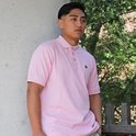 Jonge man draagt een roze poloshirt en lichtblauwe shorts.