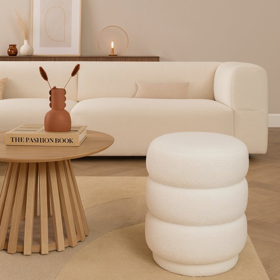 Pouf blanc en teddy à côté d'une table basse en bois dans un salon.