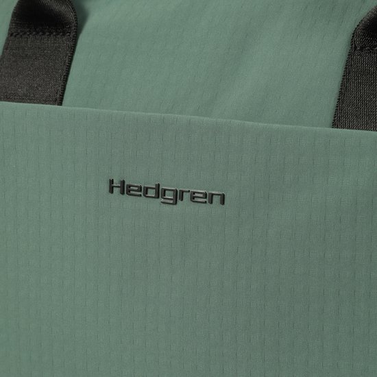 Close-up van het zwarte Hedgren logo op een groene, textuurstof rugzak.