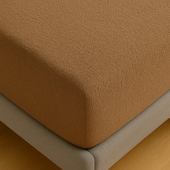Close-up van een taupe hoeslaken met een subtiel, hobbelig textuurpatroon.