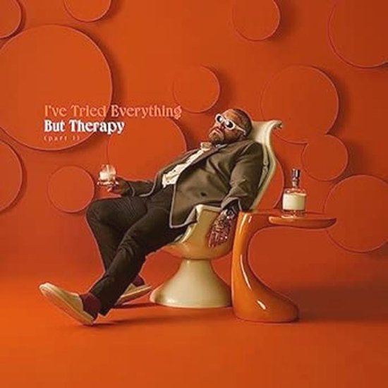 Man met zonnebril zit in stoel met glas en flesje. Tekst: I've Tried Everything But Therapy.