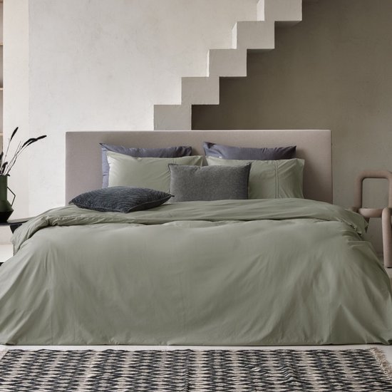 Housse de couette verte avec taies d'oreiller sur un lit, avec un escalier stylisé en arrière-plan.