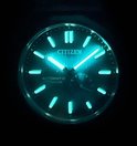 Glow-in-the-dark foto van de wijzerplaat van een Citizen horloge. Lichtgevende indices en wijzers op een blauwe achtergrond.