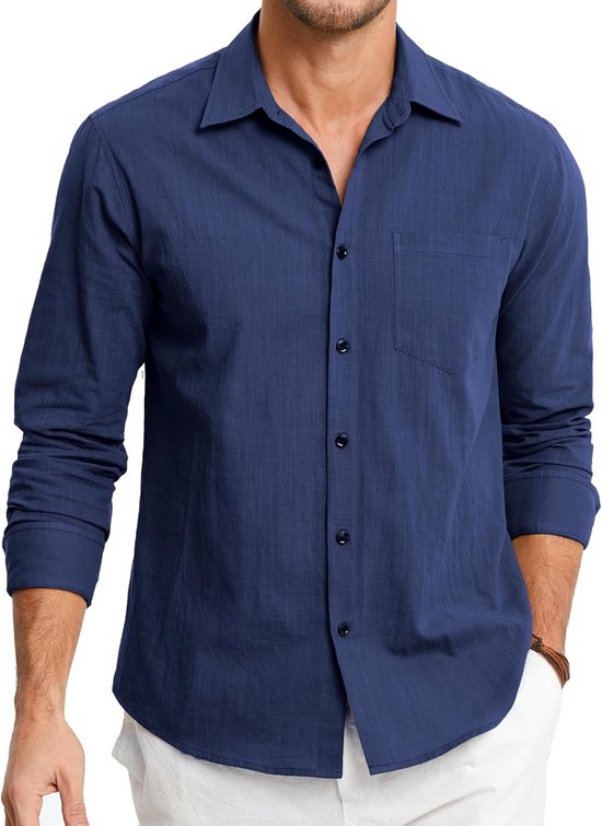 Model draagt een marineblauw hemd met lange mouwen, kraag, knoopsluiting en borstzak op een witte broek.