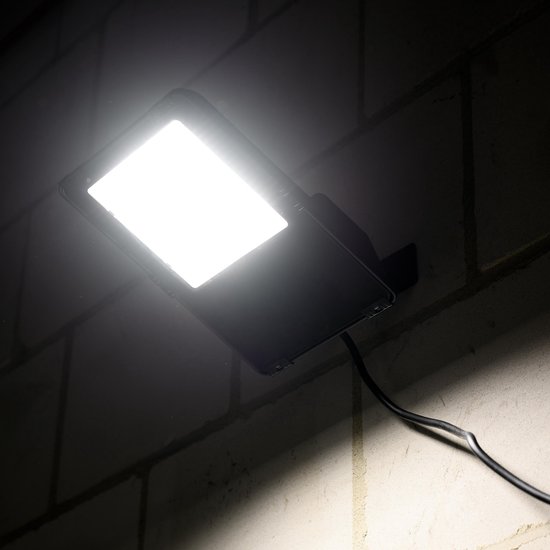 Verlichte zwarte LED-schijnwerper gemonteerd op een bakstenen muur.