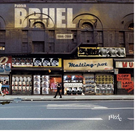 Albumcover 'Puzzle' van Patrick Bruel. Een straatbeeld met een gebouw met de naam Patrick Bruel erop. Op de etalages staan posters van Patrick Bruel.