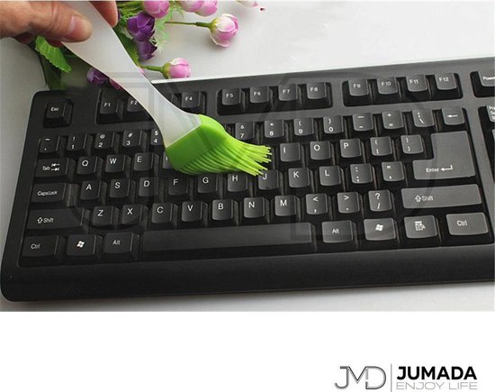 Een groene siliconen bakkwast wordt gebruikt om een toetsenbord schoon te maken.