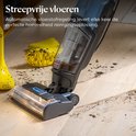 Een stofzuiger met ledverlichting bij de borstelkop zuigt vuil op van een houten vloer. Een paar gele laarzen liggen ernaast.