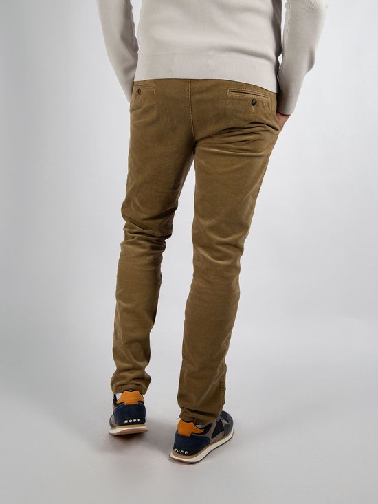 De achterkant van een man die een beige corduroy broek en sneakers draagt.