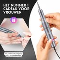 Handen voeren manicure uit met zilverkleurige nagelvijl. De ideale cadeautip voor vrouwen.
