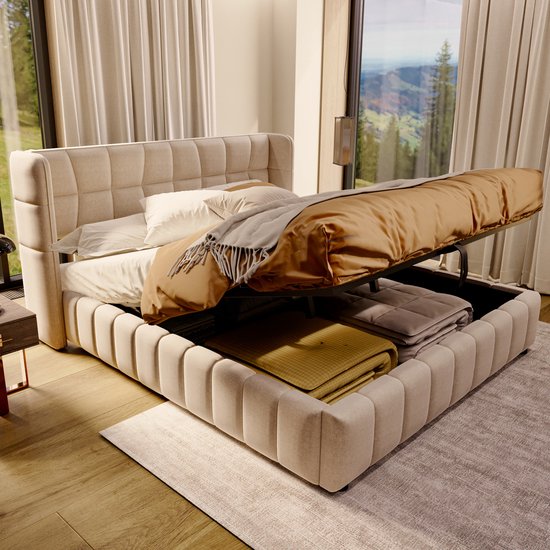 Beige gestoffeerd bed, bedbodem opgelicht om opbergruimte te tonen met gele en grijze dekens.