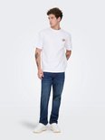 Man met wit T-shirt en donkerblauwe jeans. T-shirt heeft een kleine opdruk op de borst.