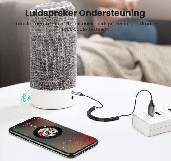 Zilverkleurige Ugreen Bluetooth adapter aangesloten op grijze luidspreker.