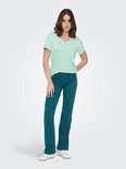 Model in lichtgroen t-shirt met V-hals en donkergroene broek.
