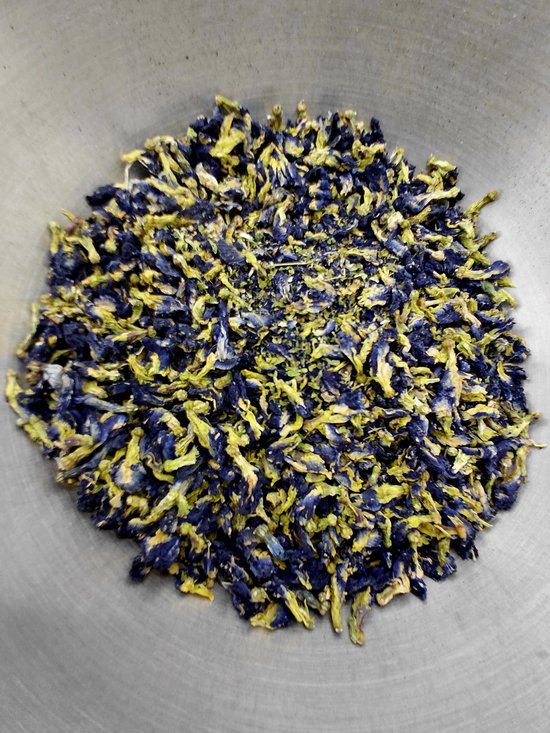Gedroogde blauwe erwtbloemen in een metalen kom, met paarse en gele tinten.