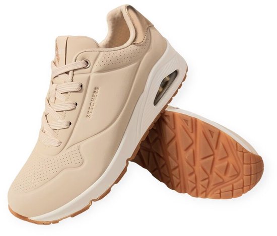 Baskets Skechers UNO naturelles à lacets, perforations et accent doré au talon. Semelle en caoutchouc texturé.
