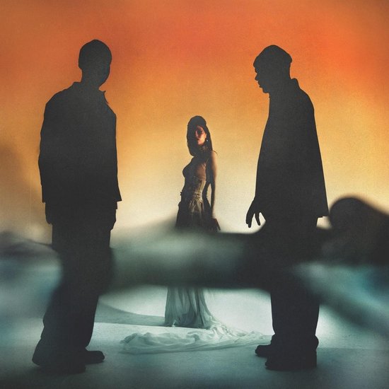 Silhouettes de deux hommes et une femme en robe, sur fond de ciel orangé.