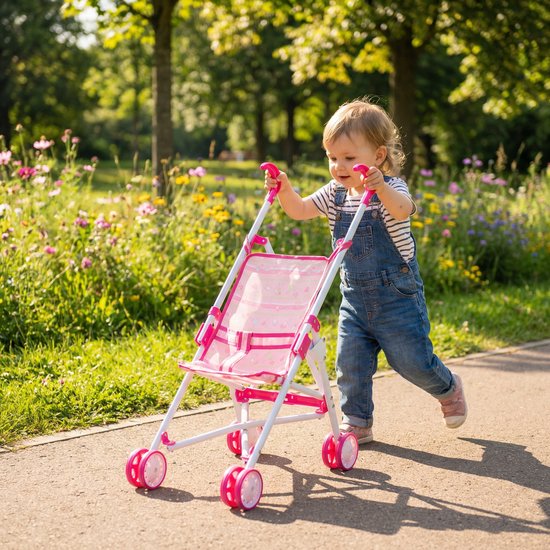 Meisje in spijkerbroek en gestreepte top duwt een roze poppenbuggy in een park.
