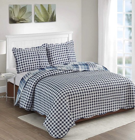 Bed opgemaakt met dekbedovertrek met blauwe en witte gingham ruit, twee kussens en een wit hoofdbord.