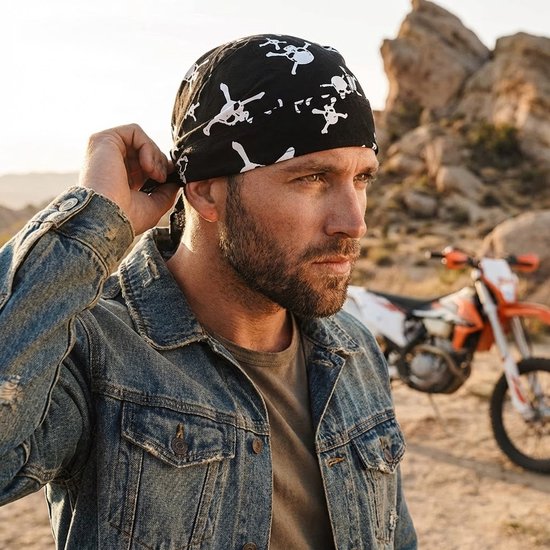 Zwart bandana met witte doodshoofdprint, gedragen door een man met een spijkerjack. Motor op de achtergrond.