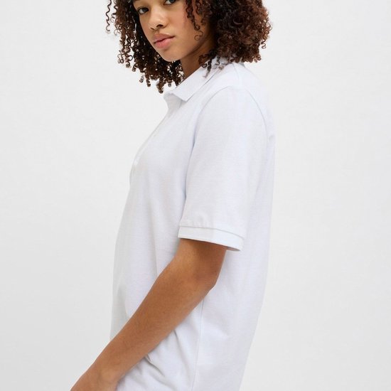 Vrouw met krullend haar, draagt een wit poloshirt, profiel.