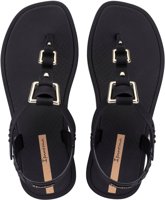 Zicht op bovenkant van zwarte Ipanema slippers met gouden gespen.