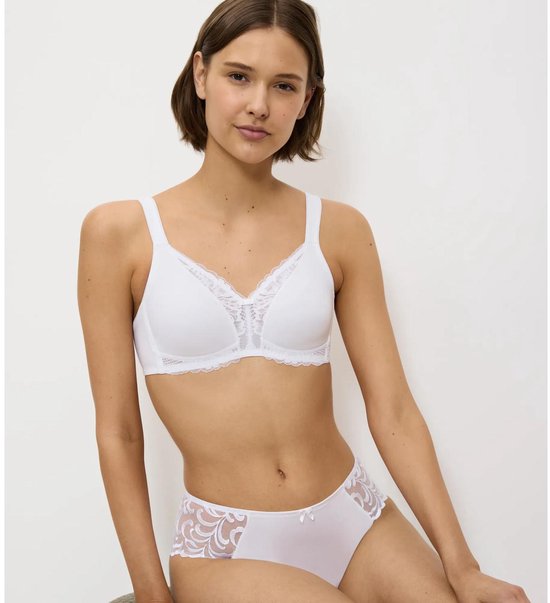 Zittend model in een witte beha met kanten afwerking en bijpassend ondergoed.