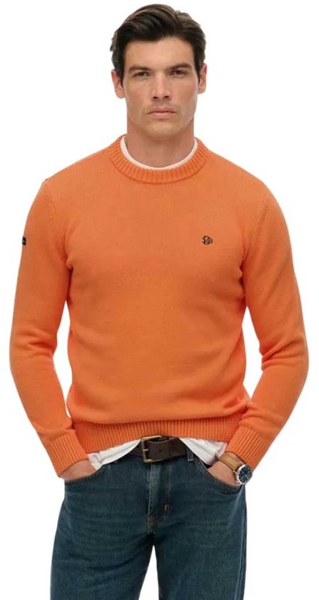 Mannequin portant un pull tricot orange à col rond, logo brodé sur la poitrine, t-shirt blanc, jean et montre.