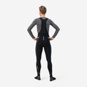 Achterkant van een man die een zwarte fietsbroek met bretels en grijze longsleeve draagt. "AQUA TE" op de enkel.