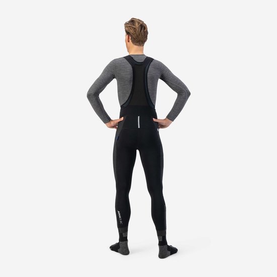 Achterkant van een man die een zwarte fietsbroek met bretels en grijze longsleeve draagt. "AQUA TE" op de enkel.