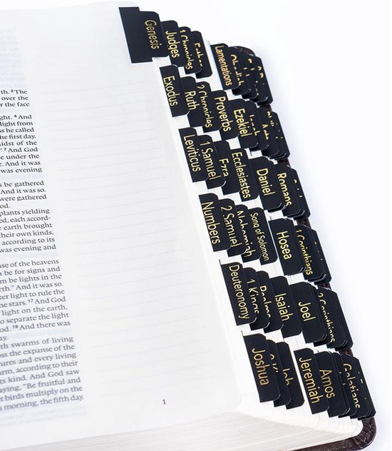 Zwarte zelfklevende bijbel-tabbladen met gouden tekst, aangebracht op een bijbelpagina.
