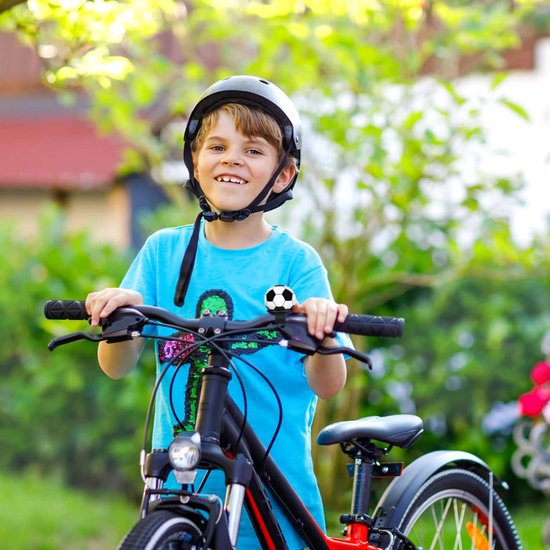 Jongen met helm en blauw shirt op een fiets, met een voetbalfietsbel op het stuur.