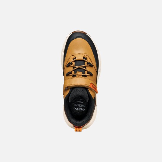 Bruine sneaker met zwarte en oranje accenten, oranje lus en klittenbandsluiting.