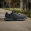 Zwarte Adidas Terrex trailrunningschoen met op de zijkant 'TERREX' logo, op een bospad.