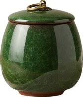Donkergroene keramieken urn met deksel, met gouden ringdetail. Geïsoleerd op witte achtergrond.