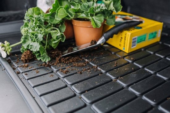 Een zwarte automat met aarde, planten en een tuinschepje.