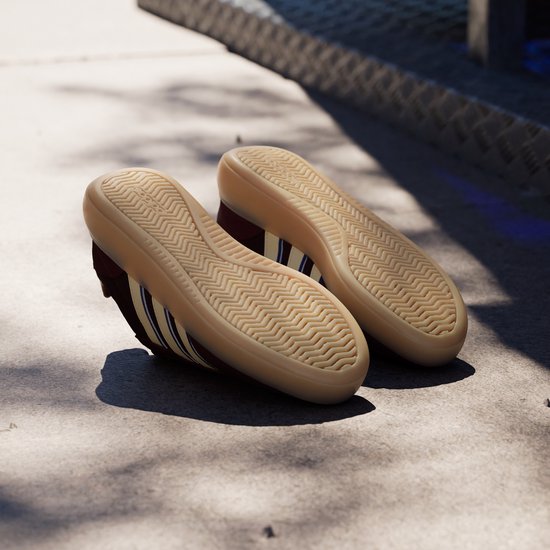 Zolen van bordeauxrode sneakers met beige zolen en Adidas logo.