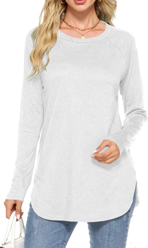 Une femme porte un haut long gris clair à col rond et manches raglan longues. Le haut est ample et présente un ourlet arrondi.