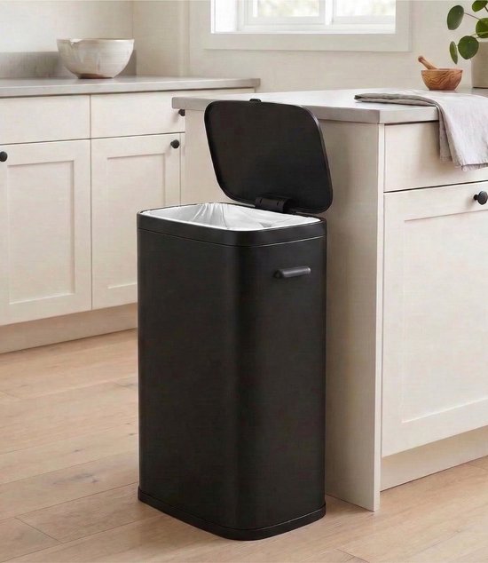Zwarte prullenbak met open deksel en vuilniszak in een keuken.