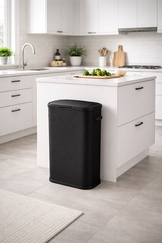 Zwarte prullenbak met gesloten deksel op een wit keukeneiland in een moderne keuken.